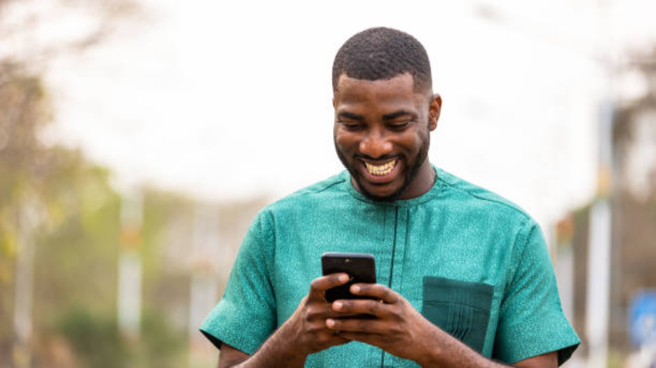 Young African Man Mobile banking on-the-go with smartphone, Portrait of Ghanaian man holding cellphone